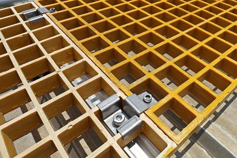 Adjacent FRP grating panels joined in the field with stainless steel clips and bolt assemblies