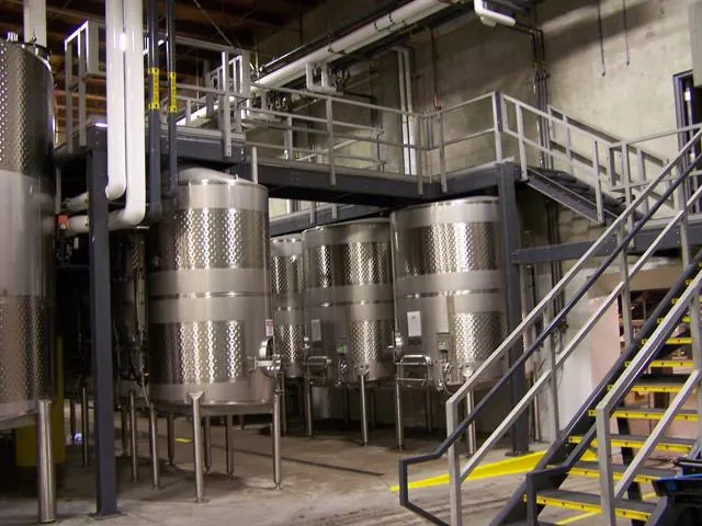 Stainless steel process tanks with FRP grating platforms and anti-slip stairways in a beverage plant
