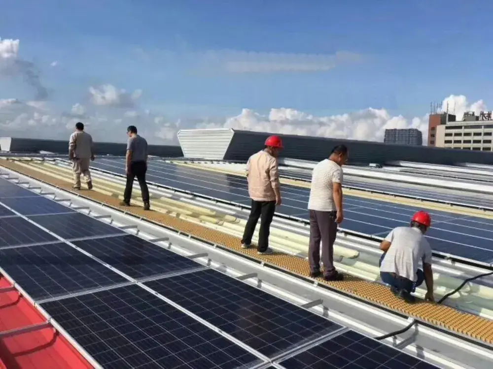 Technicians inspecting PV modules on an FRP grating walkway
