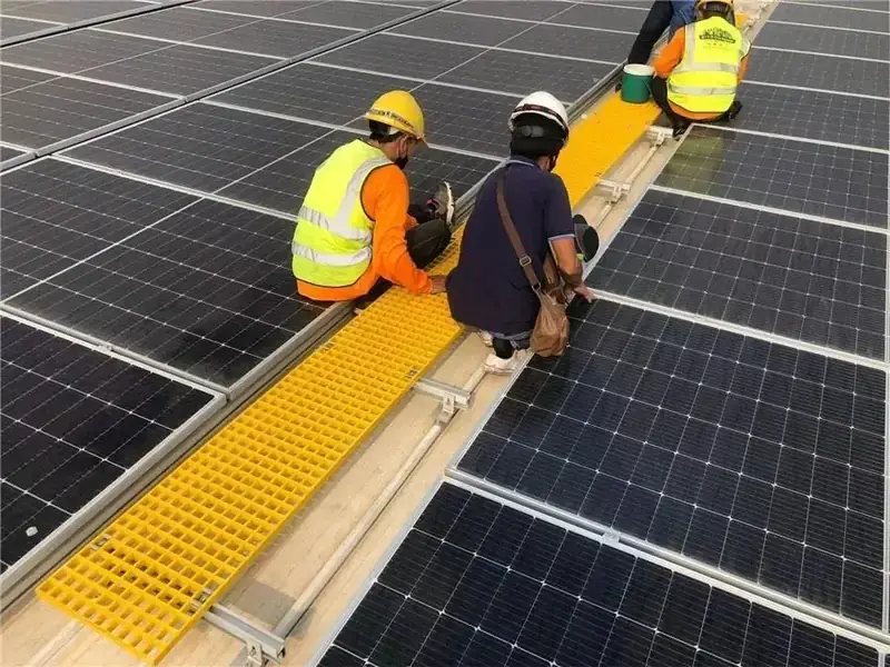 Installation crew working on an FRP grating walkway at a solar farm
